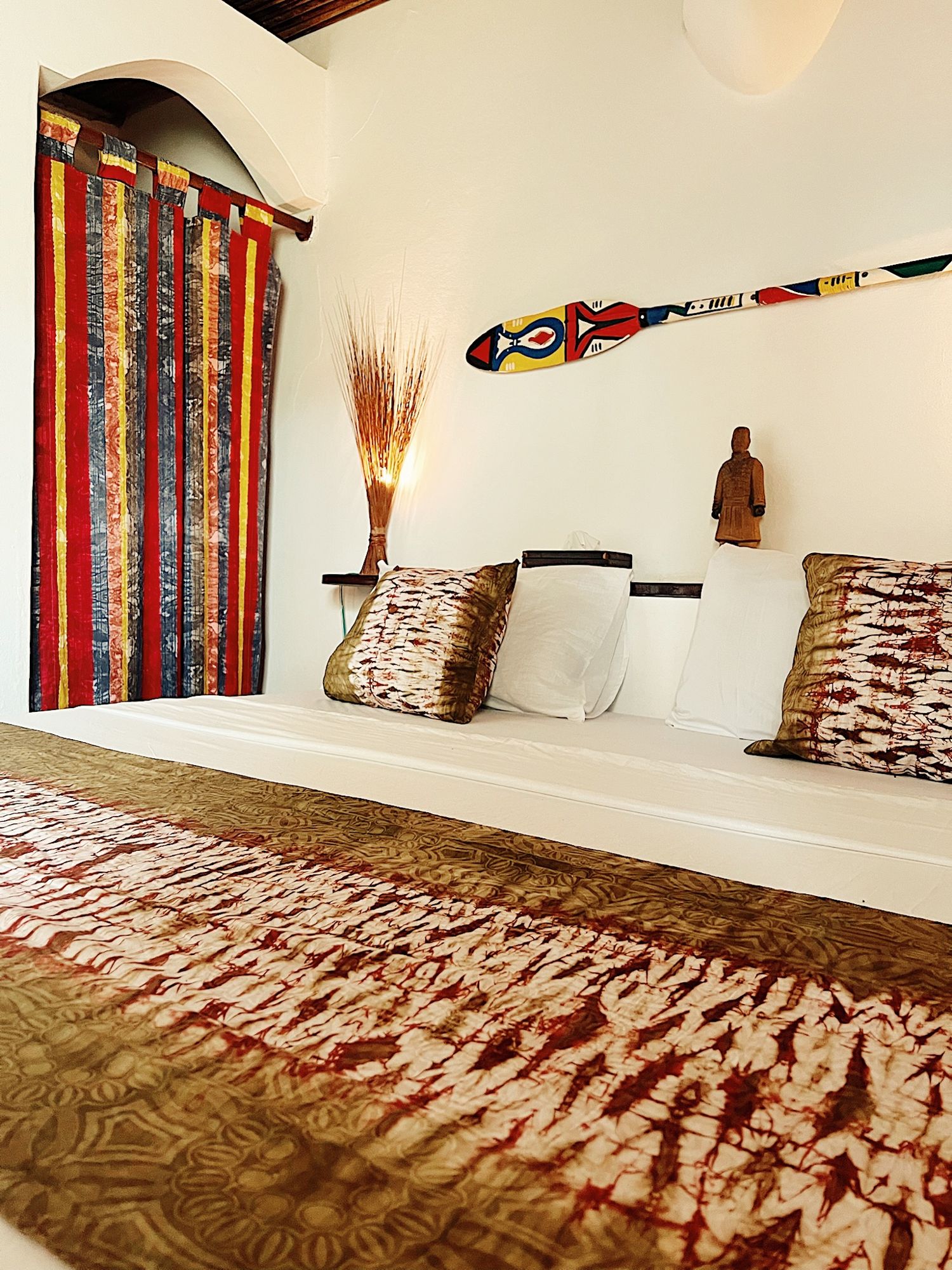 Chambre avec tenture en wax et coussins assortis