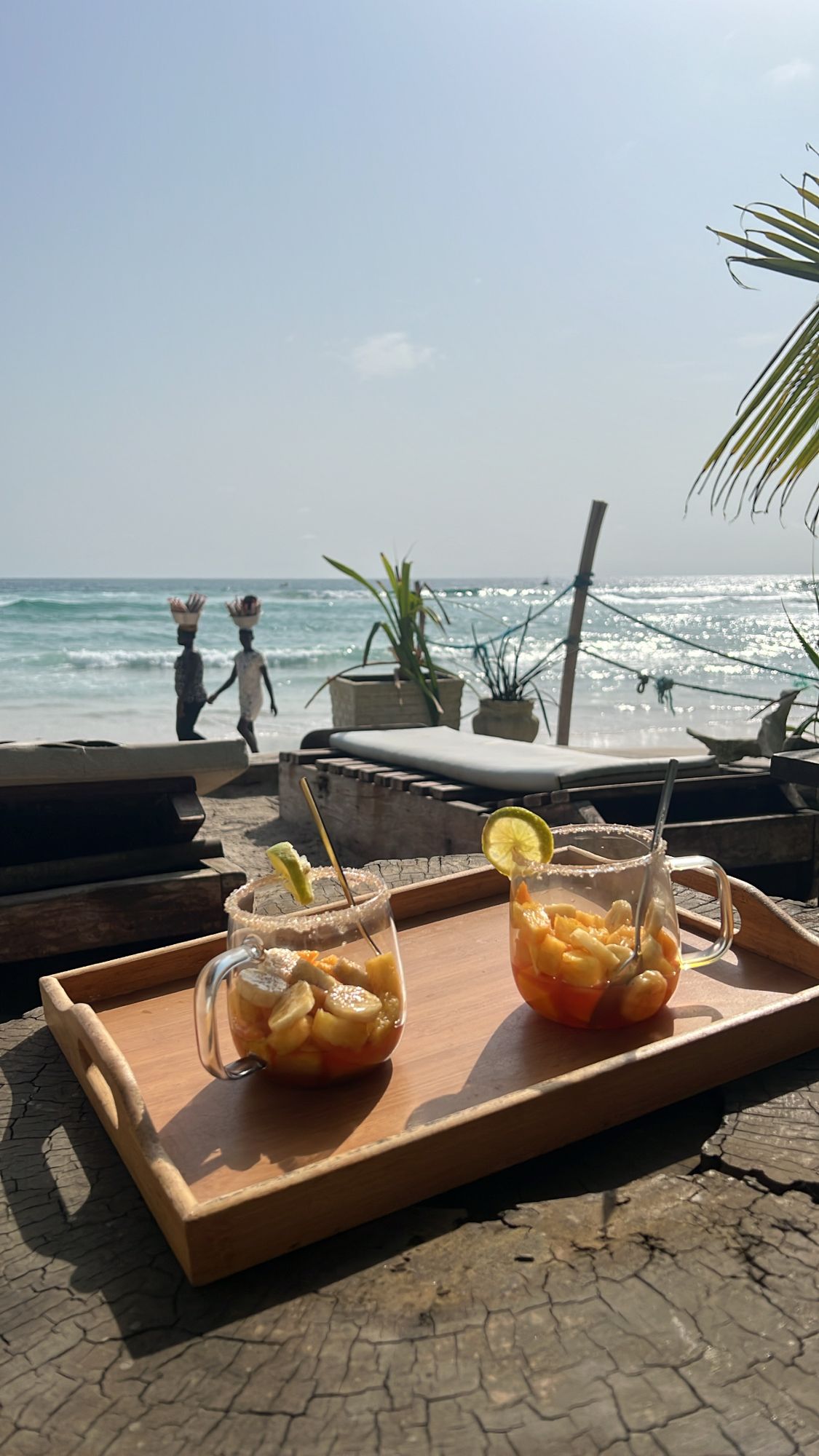 Deux cocktails servis sur un plateau en bois, face à la mer